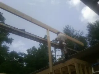 Carpenter setting a ridge beam over a new addition frame — Ice Dam Removal by Roofing Brothers in Rowland