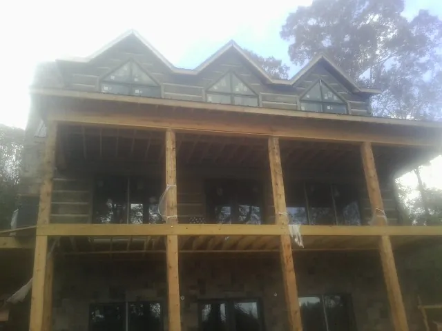 Dormers and porch framing on a large log home under construction — Roof Coating work by our crew in Rowland