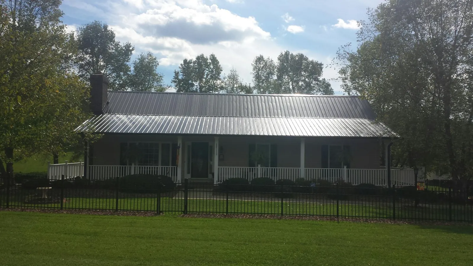 Gray metal roof on a brick ranch with a full width front porch — Gutter Guard Installation work by our crew in Rowland