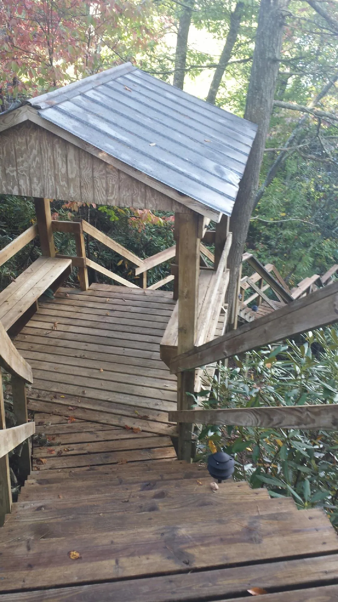 Metal roofed shelter over wooden steps on a wooded walkway — Skylight Repair & Installation work by our crew in Rowland