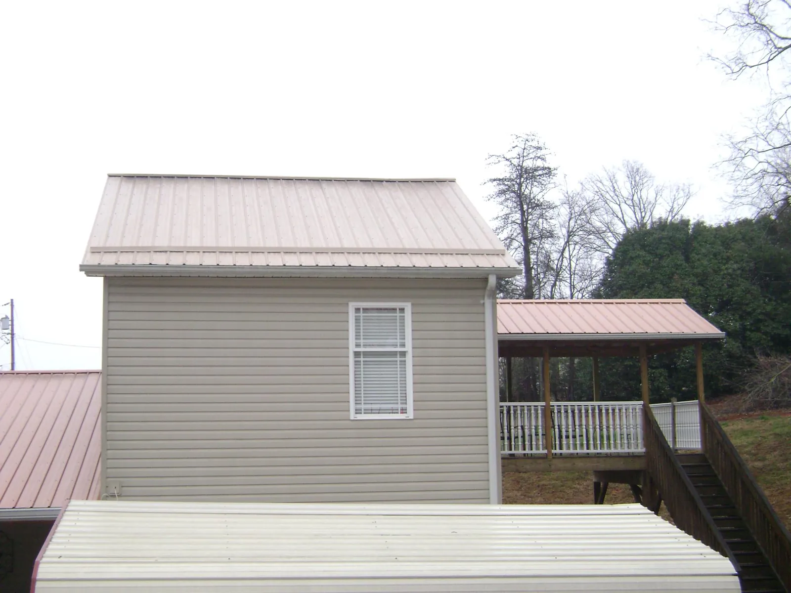 Tan metal roofs on a two story addition and attached porch, from a Roof Replacement job in Rowland