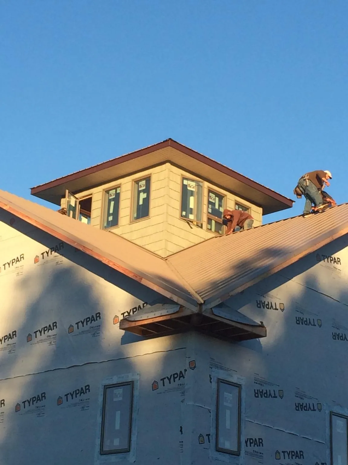 Roofers working around a rooftop cupola on a new metal roof at sunset — Roof Waterproofing in Rowland by Roofing Brothers